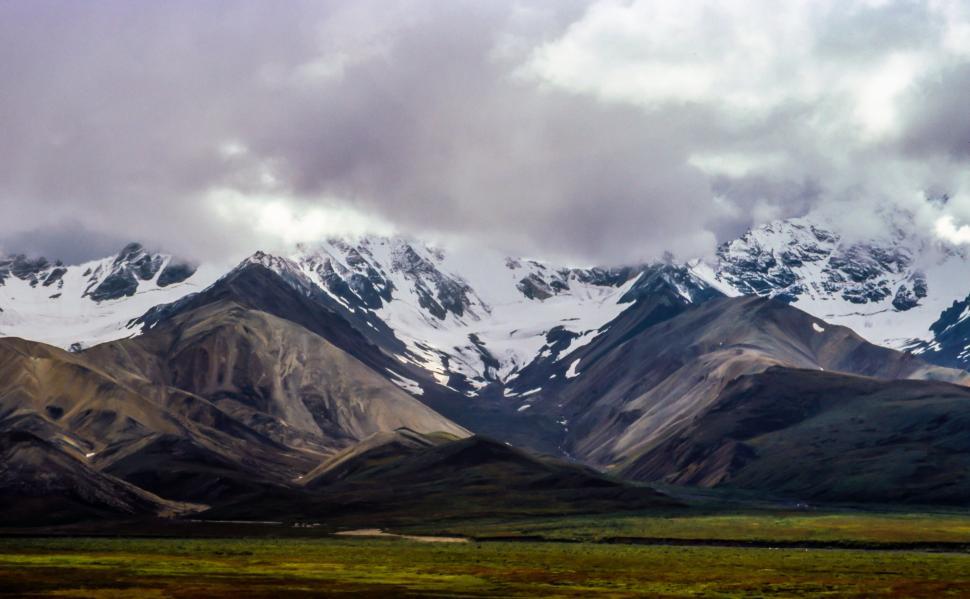 Free Image of Snow-capped mountains under a cloudy sky 