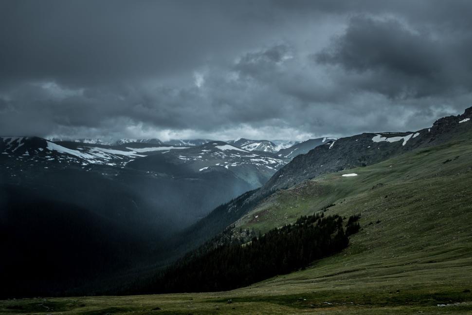 Free Image of Mountain valley under a cloudy sky with green fields 