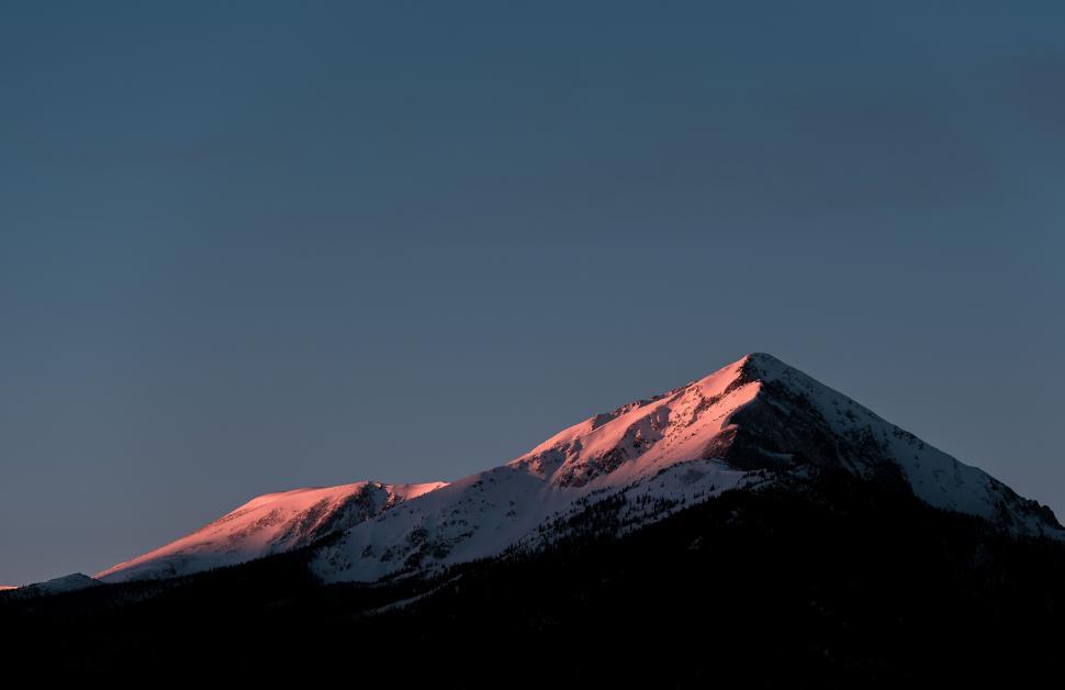 Free Image of Snow-capped mountain peak glowing under sunrise light 