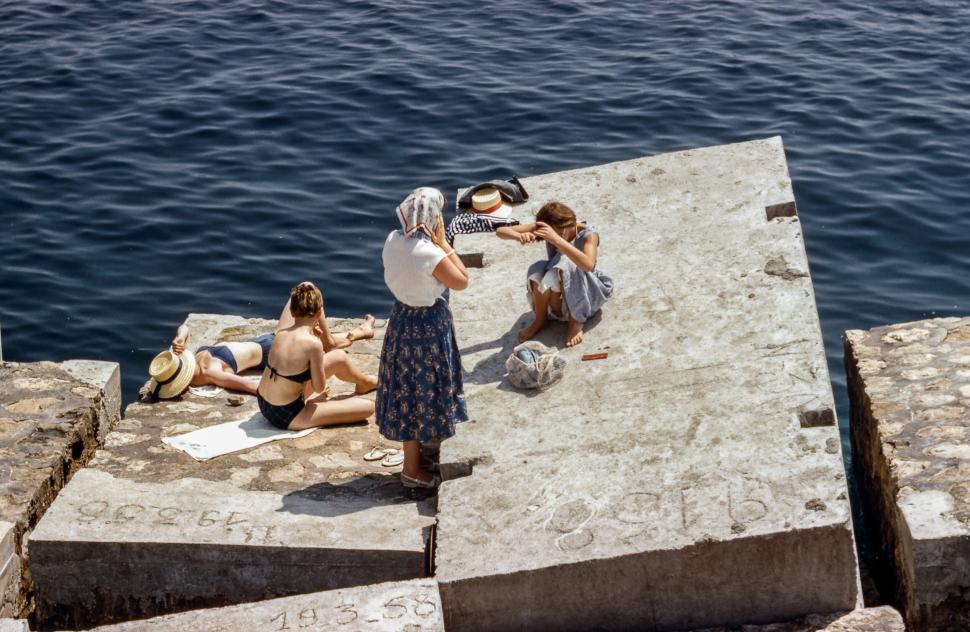 Free Image of People relaxing on concrete slabs by the water 