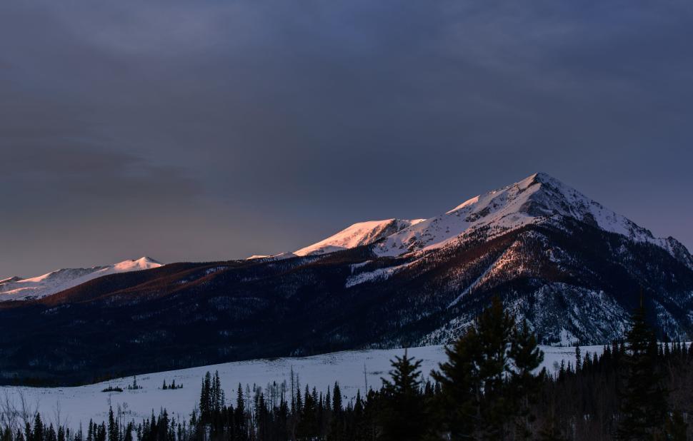 Free Image of Snowy mountain peak with hues from the setting sun. 
