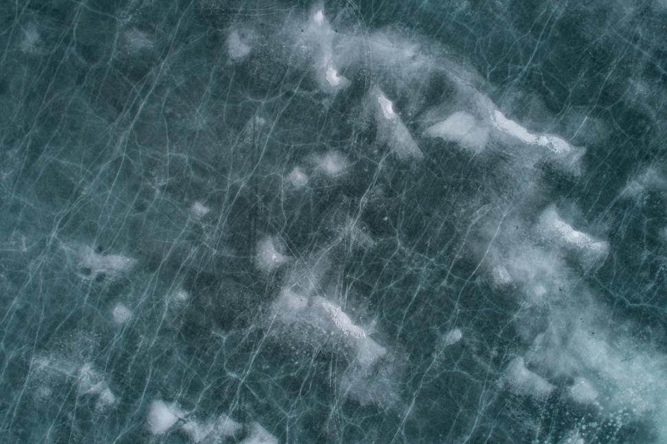 Free Image of Frozen ice surface texture with cracks and frost patches. 