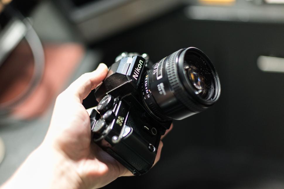 Free Image of Hand holding Nikon camera with a blurred background 