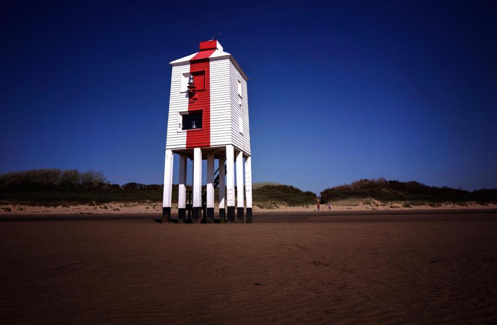 Free Image of Tall white stilt lifeguard hut on a sandy beach under clear blue sky 