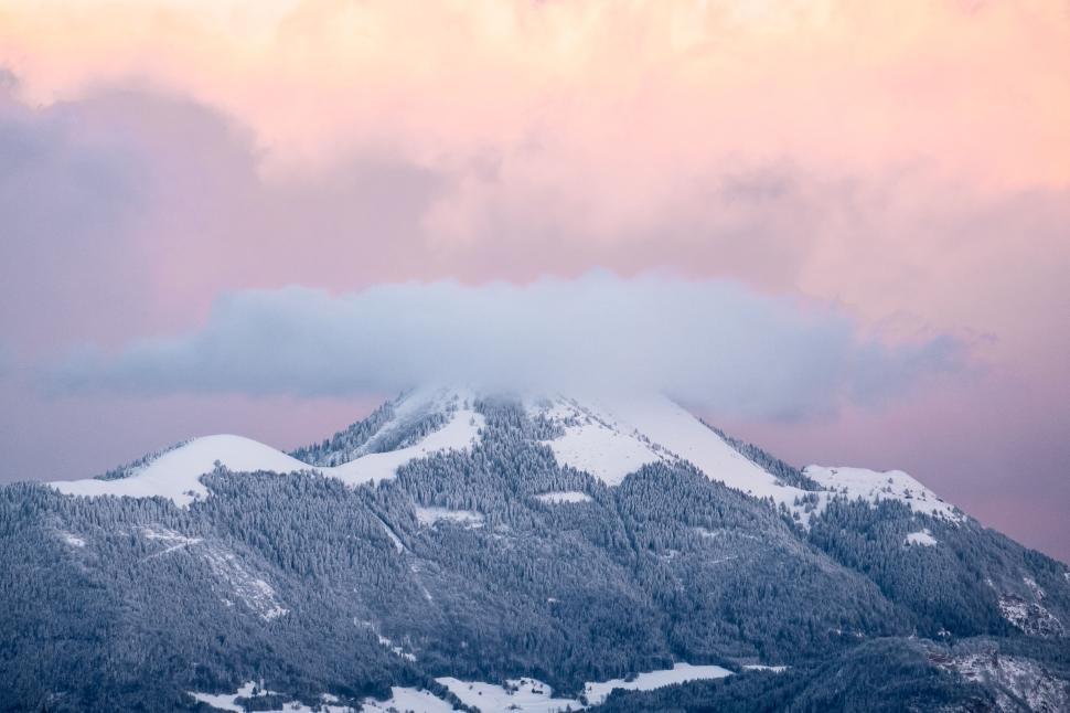 Free Image of Snow-capped mountain peak under a pastel-colored cloudy sky 