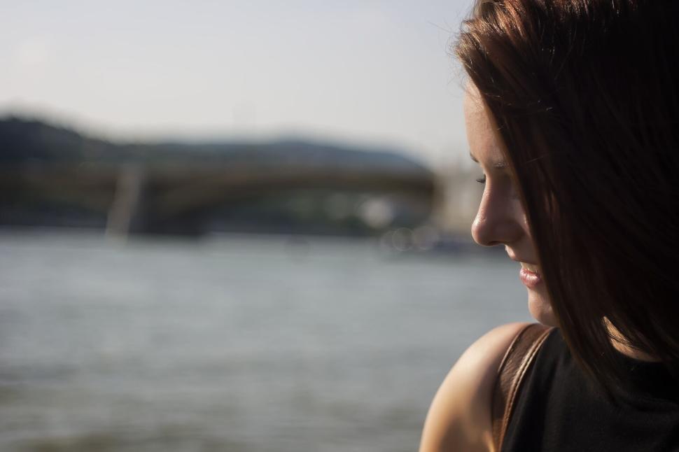 Free Image of Out of focus bridge in backdrop with a woman lost in thought. 