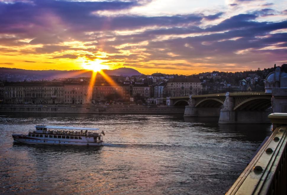 Free Image of Sunset over a river with a bridge and buildings in the background 