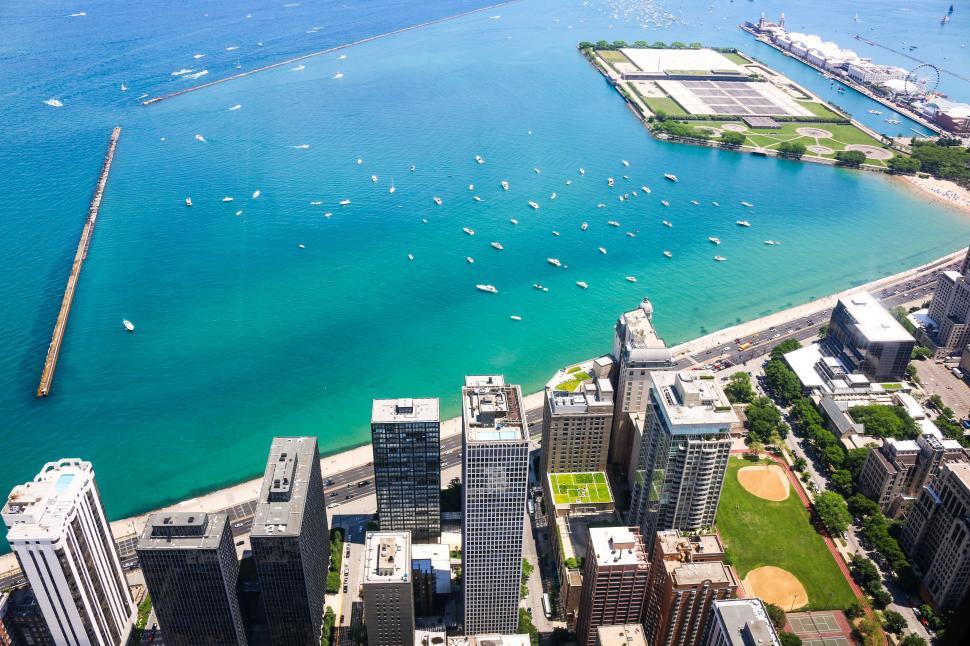 Free Image of Aerial view of city buildings alongside blue waterfront with boats. 