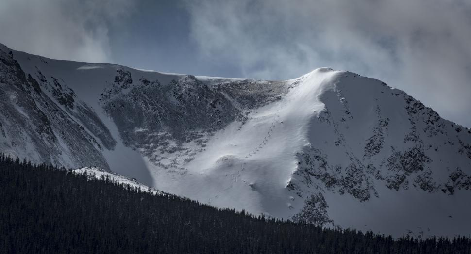 Free Image of Snow-covered mountain ridge under a cloudy sky 