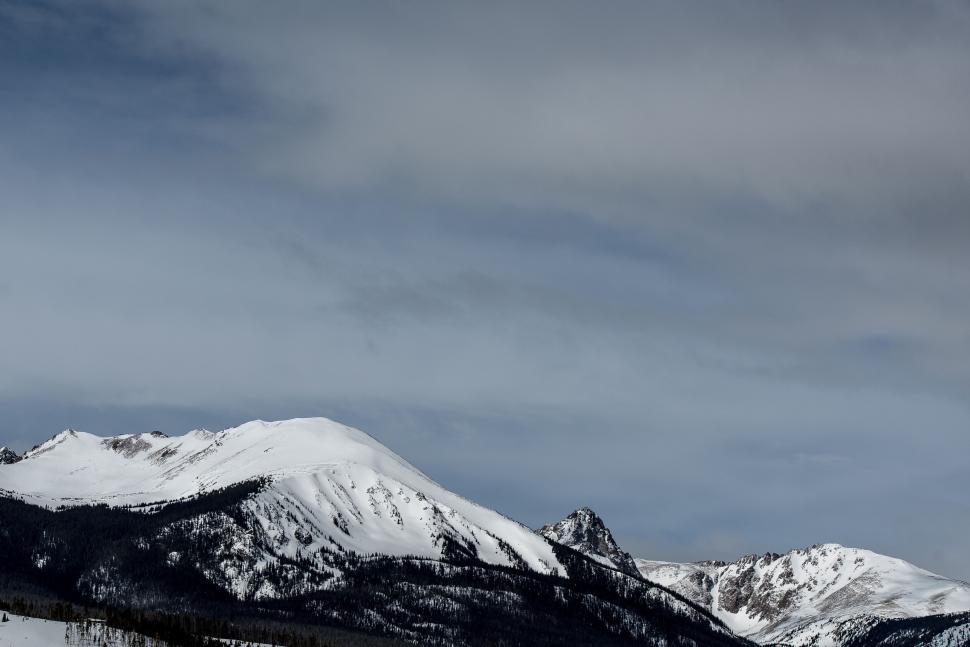 Free Image of Snow-covered mountain under a dramatic cloudy sky. 