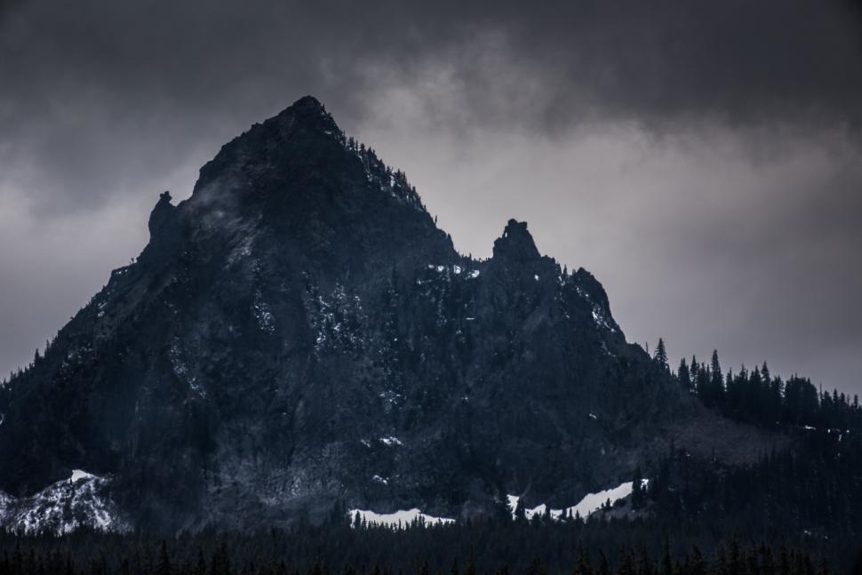 Free Image of Dark, majestic mountain peak under a brooding cloudy sky. 