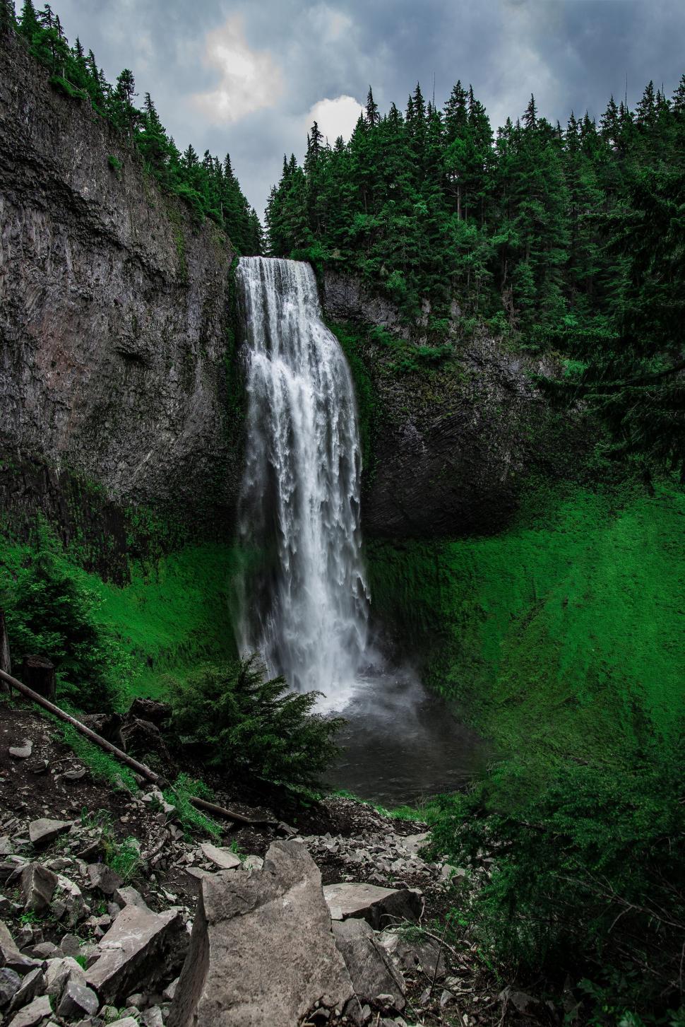 Free Image of Stunning waterfall cascading into a lush green canyon. 