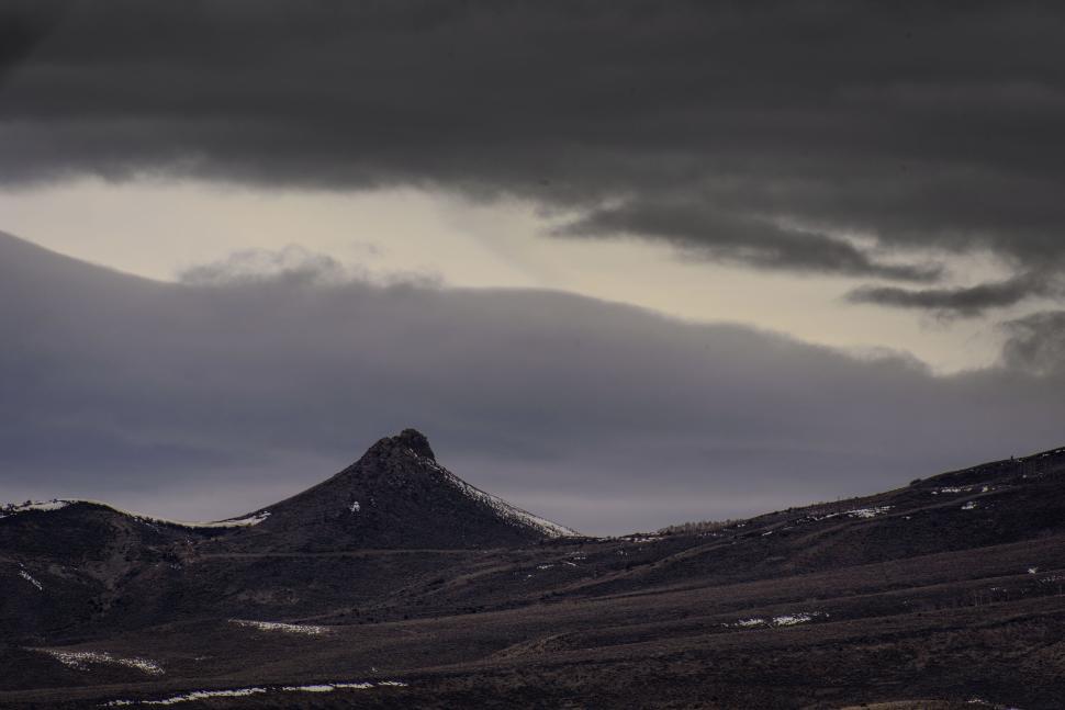 Free Image of Lonely mountain peak under foreboding, darkened skies. 