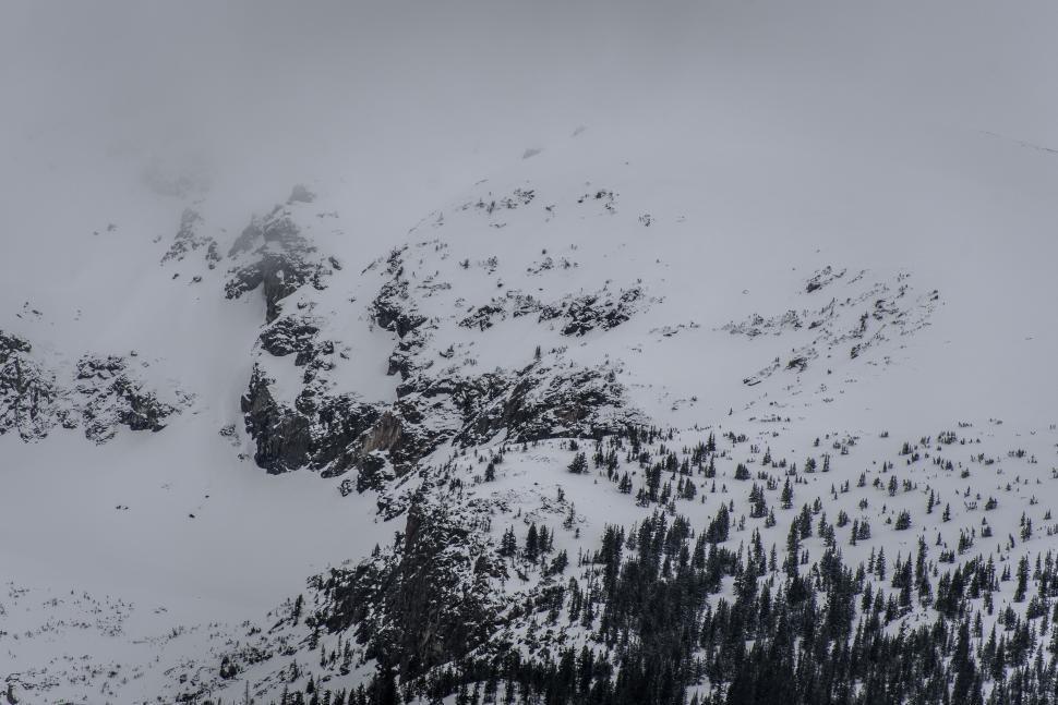Free Image of Snow-covered mountainous landscape shrouded in mist. 