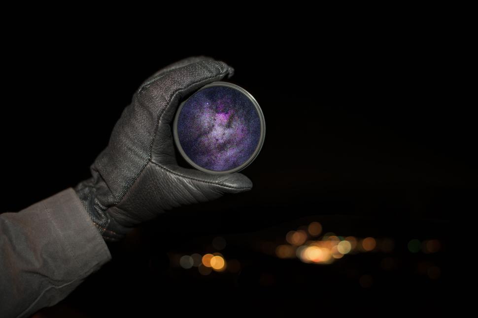 Free Image of Hand holding a lens with the Milky Way visible inside it 