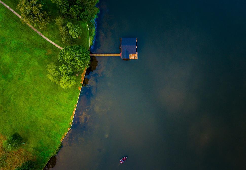Free Image of Aerial view of lakeside dock with small boat floating nearby. 