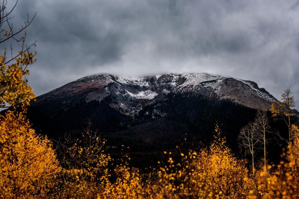 Free Image of Snow-capped mountain peak with vibrant autumn foliage below. 