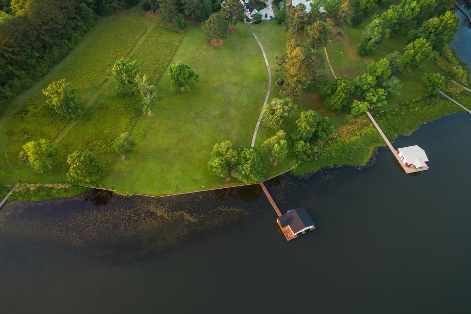 Free Image of Aerial view of a lakeside dock amidst green forested landscape 