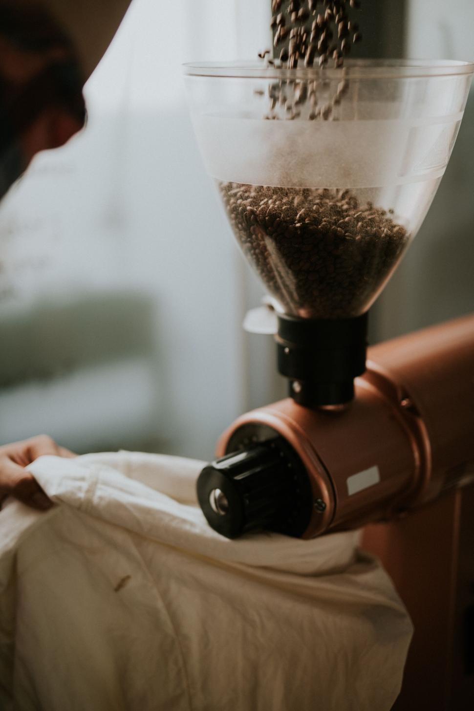 Free Image of Coffee beans being ground through a professional machine. 