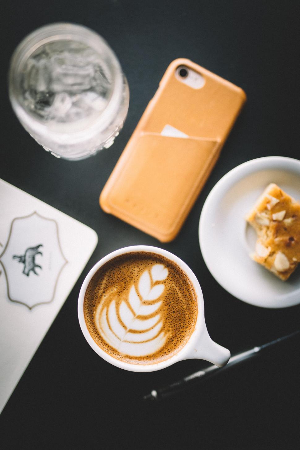 Free Image of Cup of latte with foam art on a table with other items 