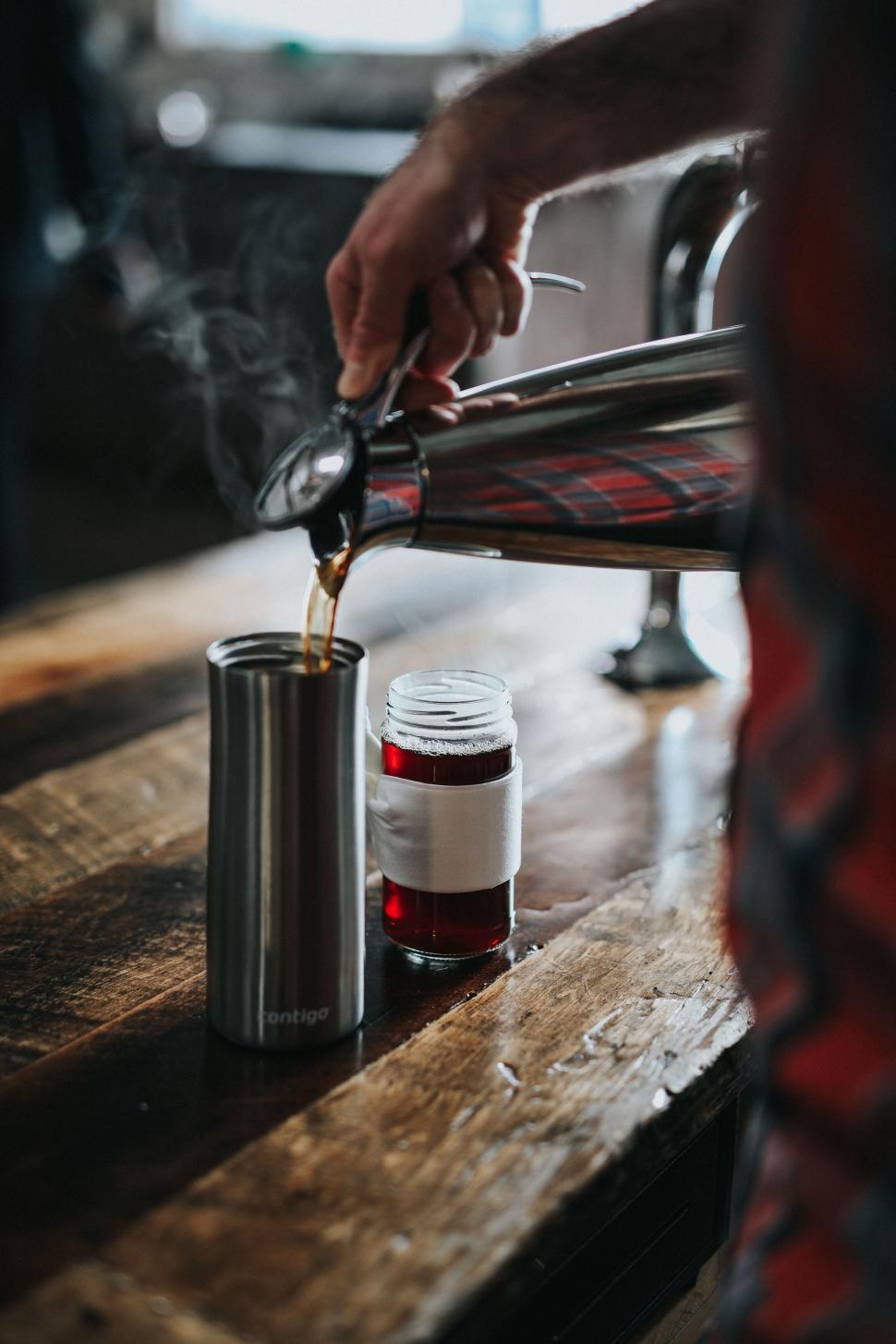 Free Image of Pouring coffee into a thermos on a wooden table 