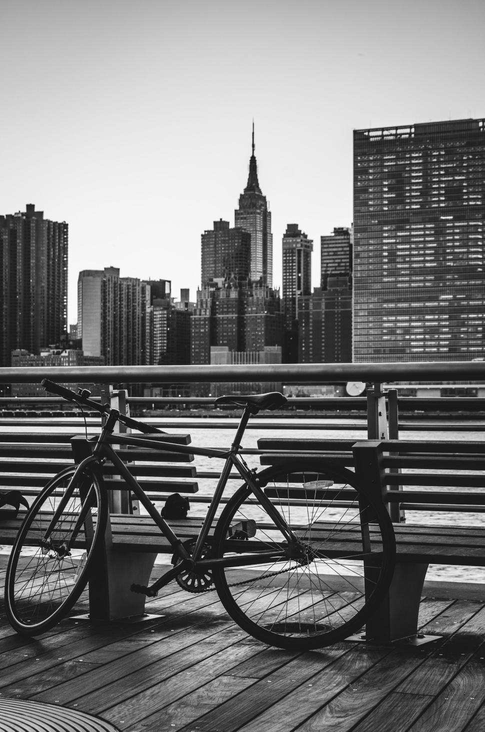 Free Image of Bicycle parked by the railing with city skyline behind 
