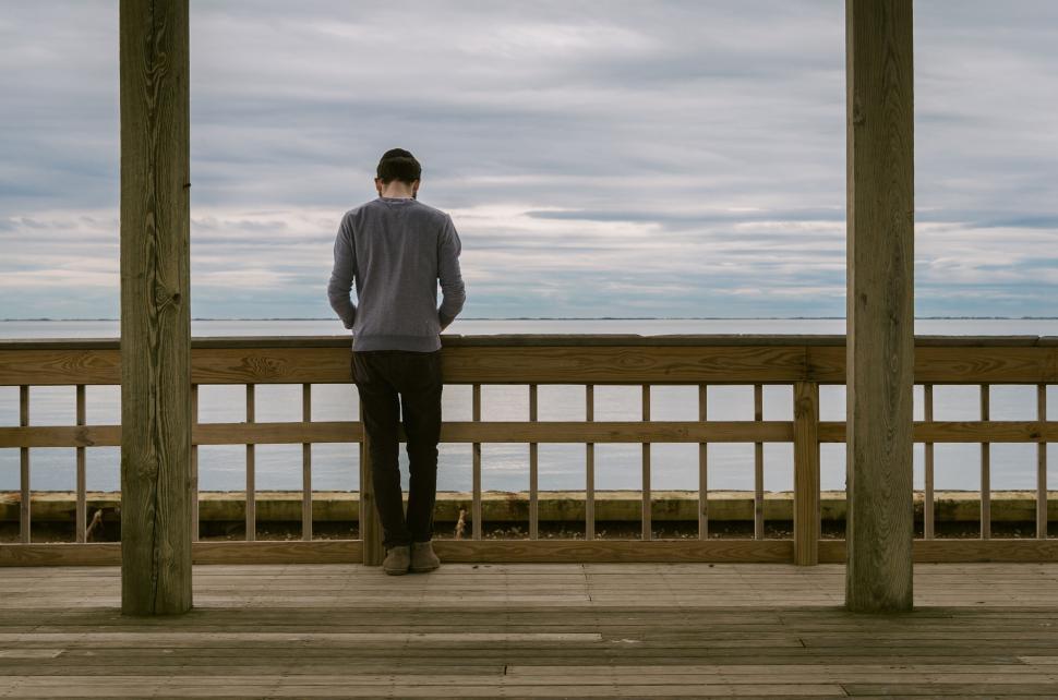 Free Image of Alone person standing at wooden deck overlooking the sea 