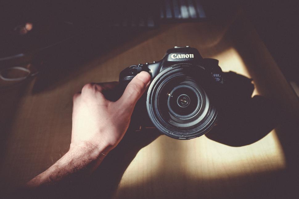 Free Image of Hand holding a Canon camera under natural light shadow 
