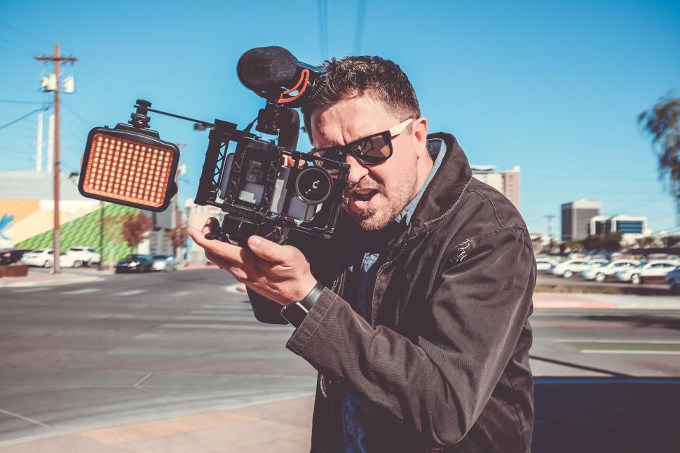Free Image of Man with video camera capturing urban scenes outside. 