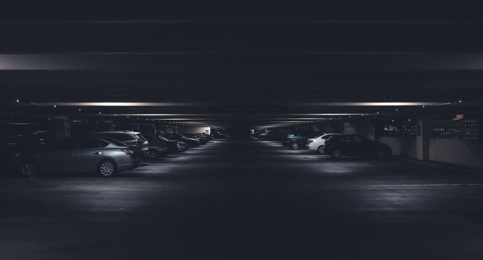 Free Image of Dimly lit parking garage with parked cars visible 