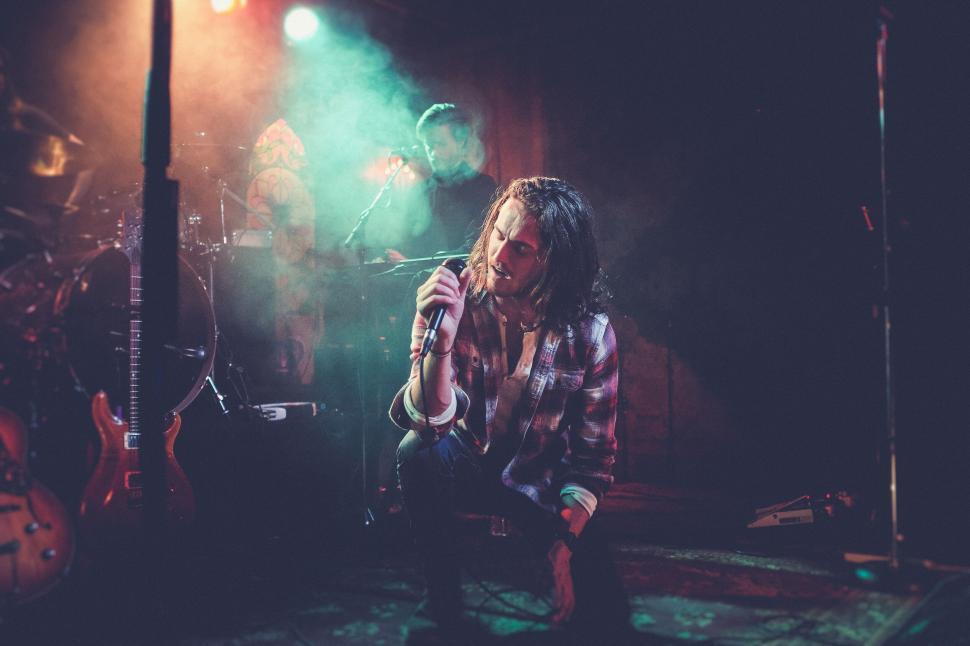 Free Image of Musician with microphone performing energetically on stage. 