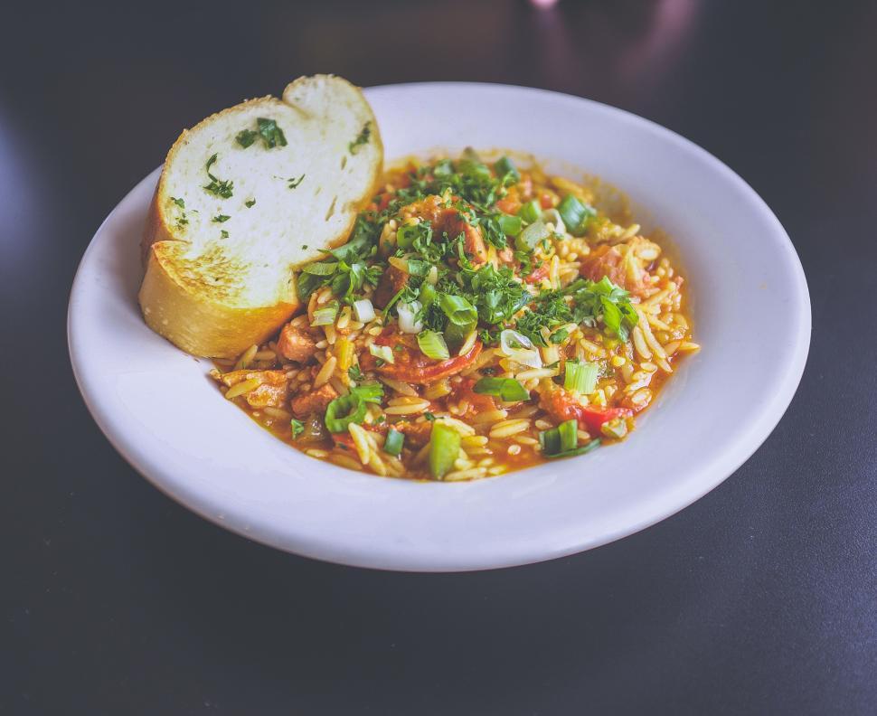 Free Image of Bowl of savory soup with bread on dark table surface. 