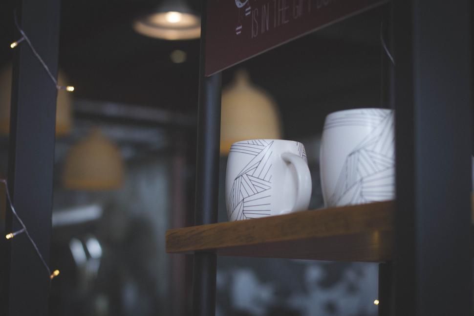 Free Image of Two white ceramic mugs on wooden shelf in a store 