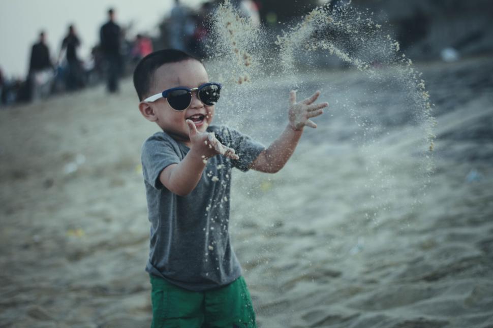 Free Image of Child playing with sand at the beach on a sunny day. 