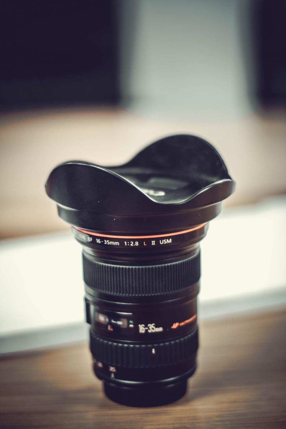 Free Image of Camera lens standing upright on a wooden surface. 