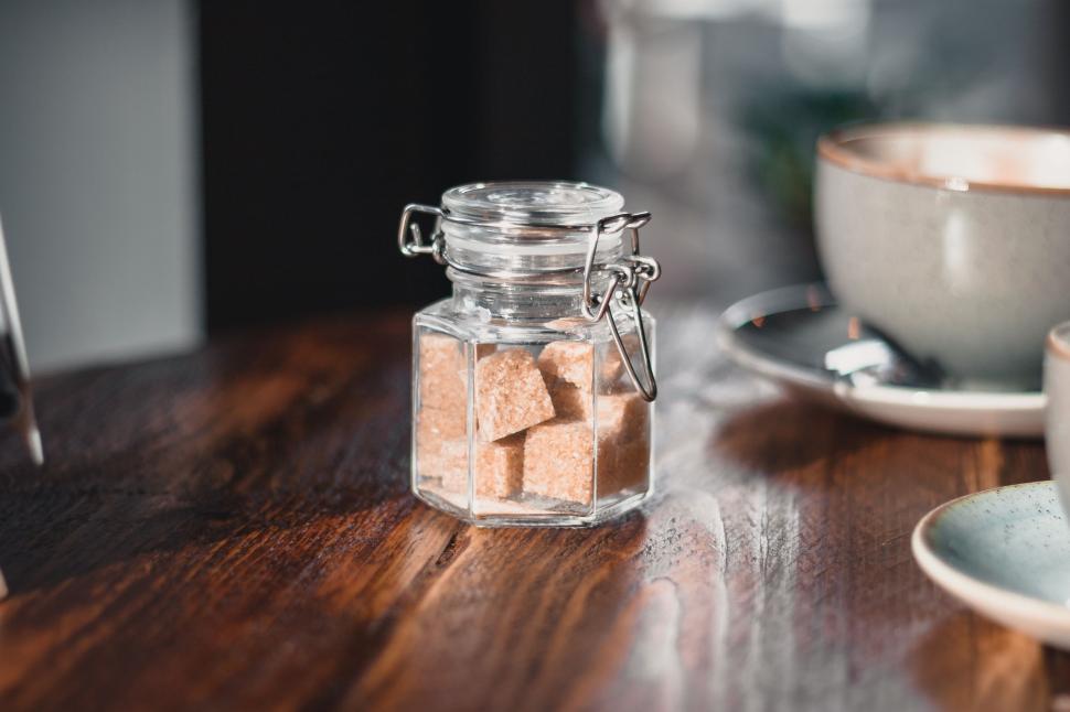 Free Image of Glass jar filled with cubes on a wooden table. 