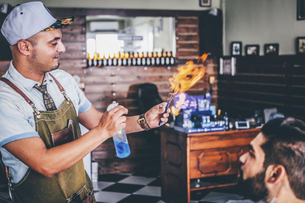 Free Image of Barber holds flaming tools while client waits in chair. 
