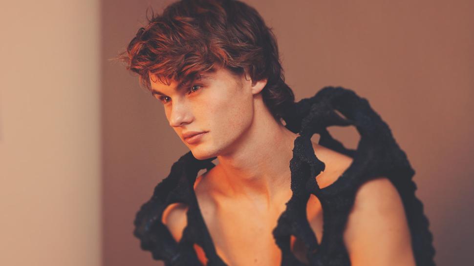 Free Image of Man with unique black textured garment looks aside. 