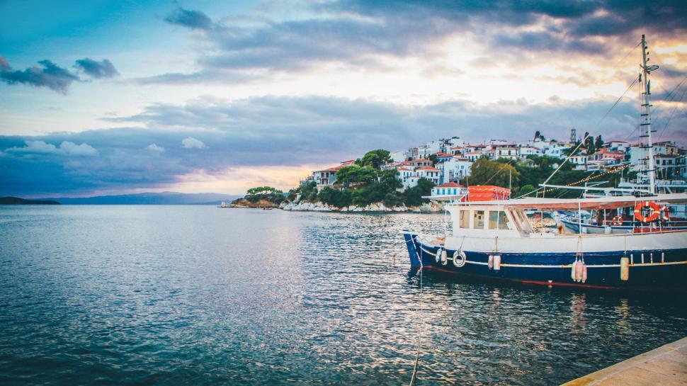 Free Image of Docked boat by the coastline under cloudy blue sky dusk. 