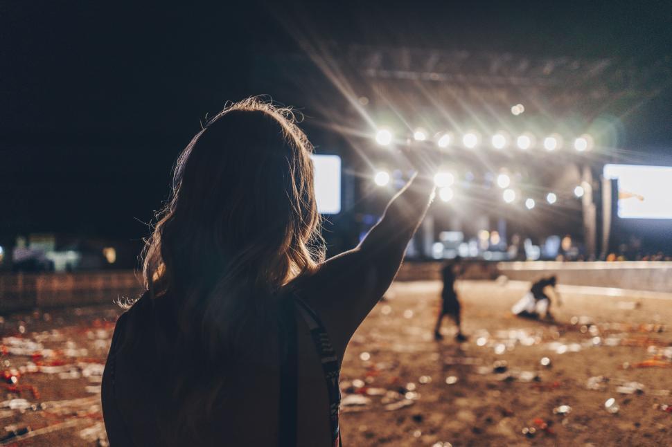 Free Image of Excited concert attendee pointing towards the stage lights 