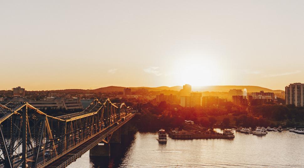 Free Image of Bridge across river with sunset in the background,boats. 