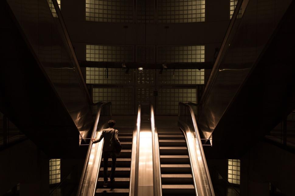 Free Image of Person on escalator inside modern, dimly lit building. 