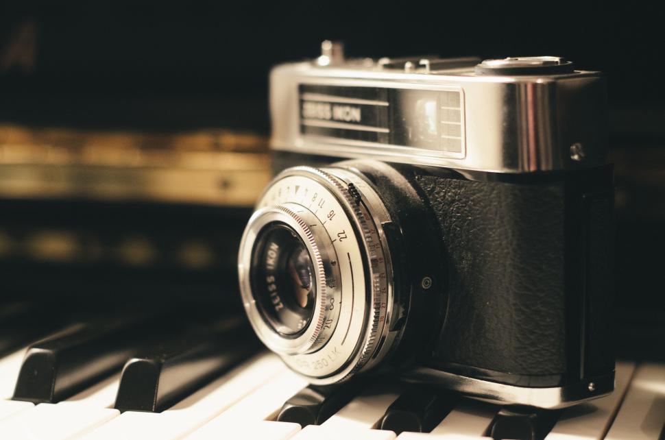 Free Image of Vintage camera on piano keys with soft light bokeh. 