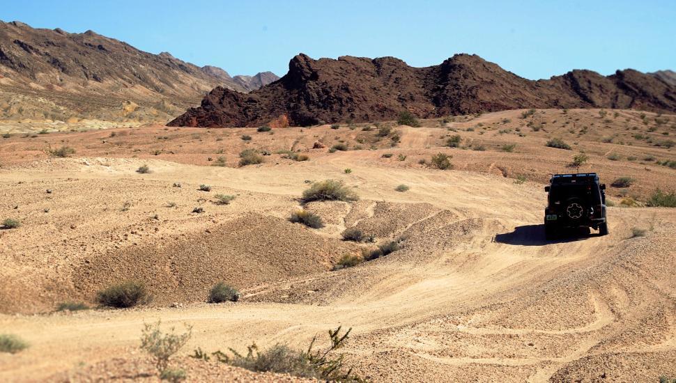 Free Image of Off-road vehicle traversing a dry, rugged desert landscape. 