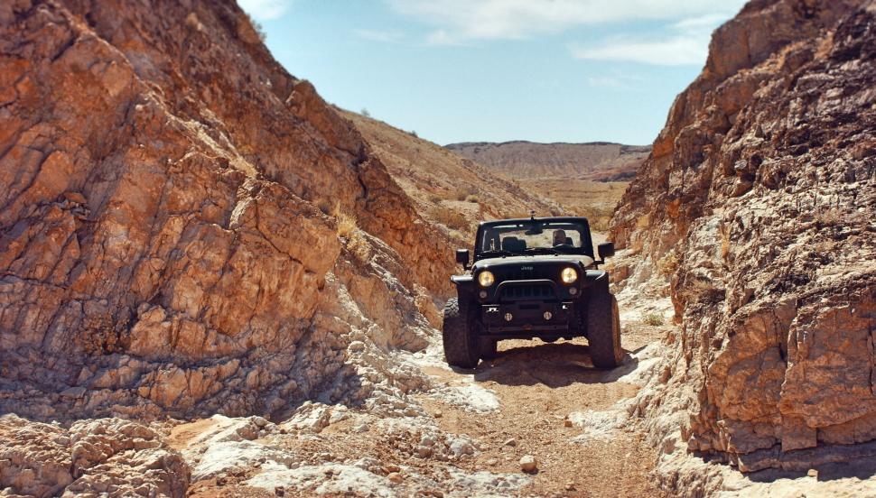 Free Image of Off-road vehicle driving through narrow rocky canyon 