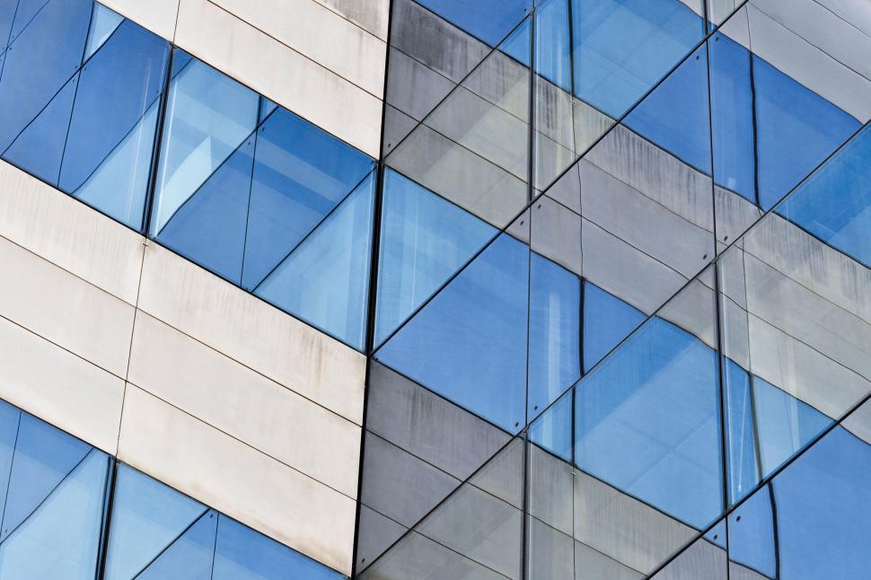 Free Image of Modern building with glass windows reflecting the sky. 