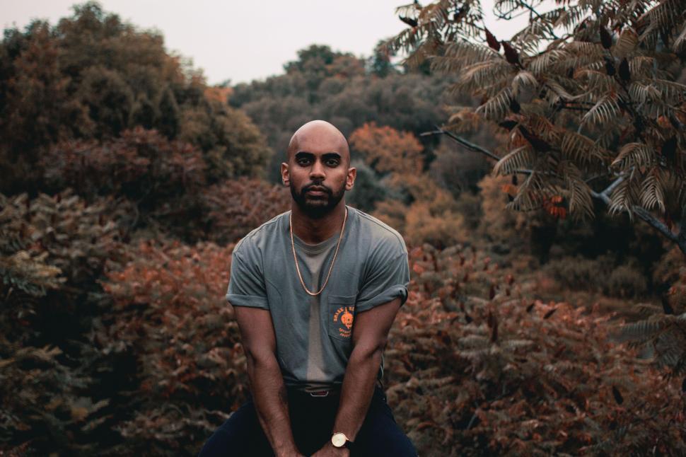 Free Image of Muscular man poses in nature with autumn foliage behind. 