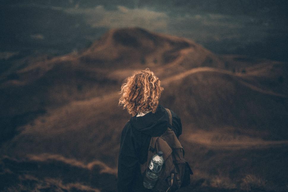 Free Image of Back view of person hiking with backpack on hilly trail 