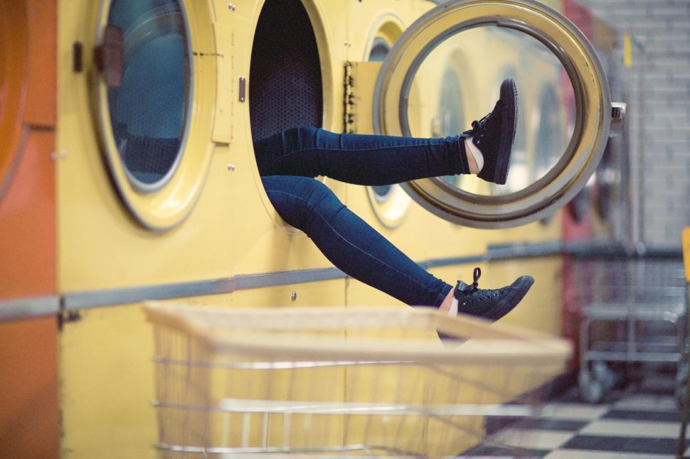 Free Image of Person legs sticking out of washing machine in laundry 