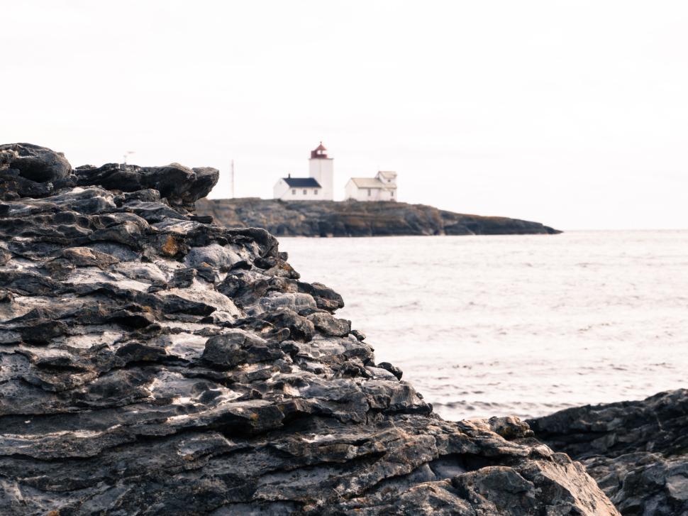 Free Image of Rocky coastline with distant lighthouse on the horizon 